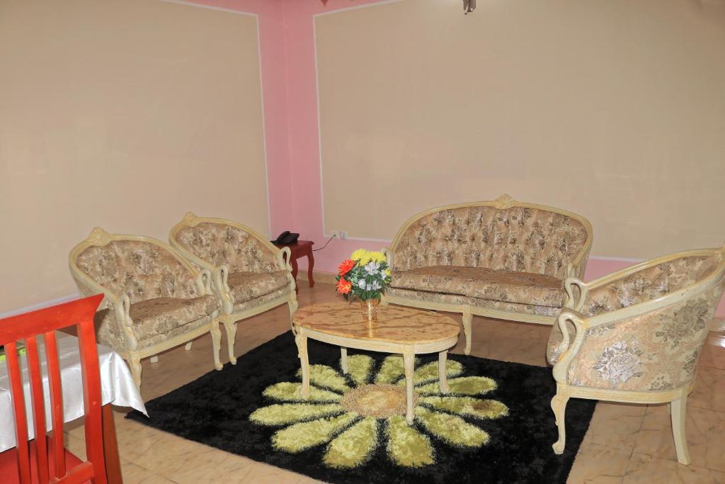a room with three chairs and a table with flowers on it at Hotel Residence Madadjeu in Yaoundé