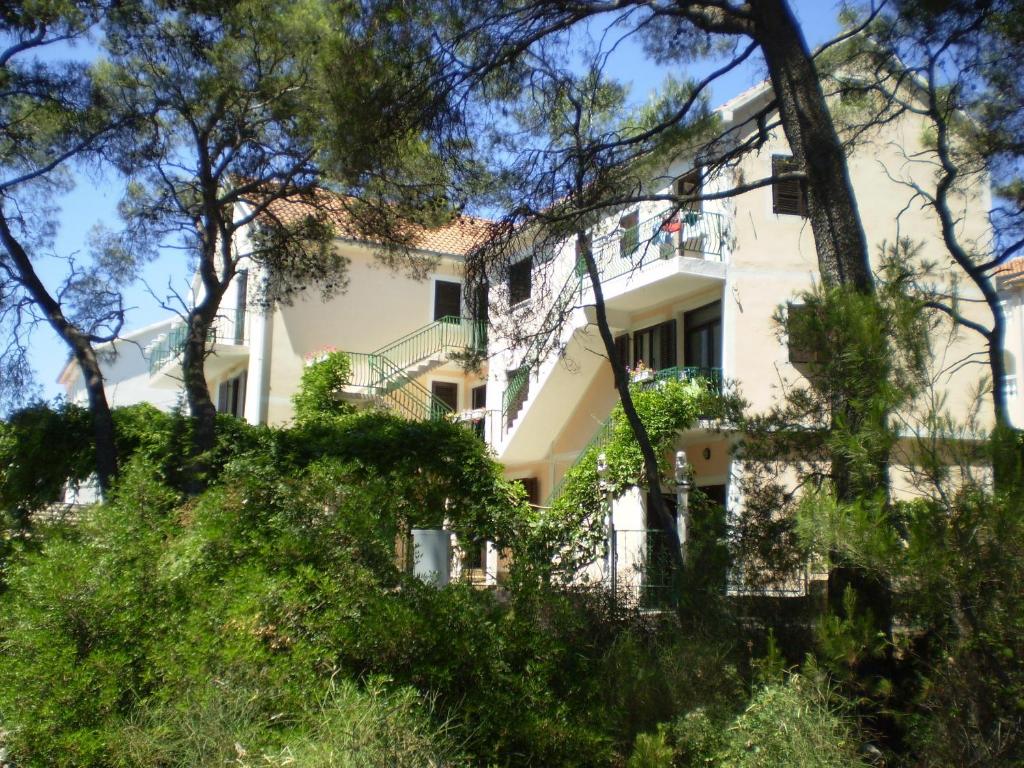 une maison blanche avec des arbres devant elle dans l'établissement Villa Welcome, à Vrboska