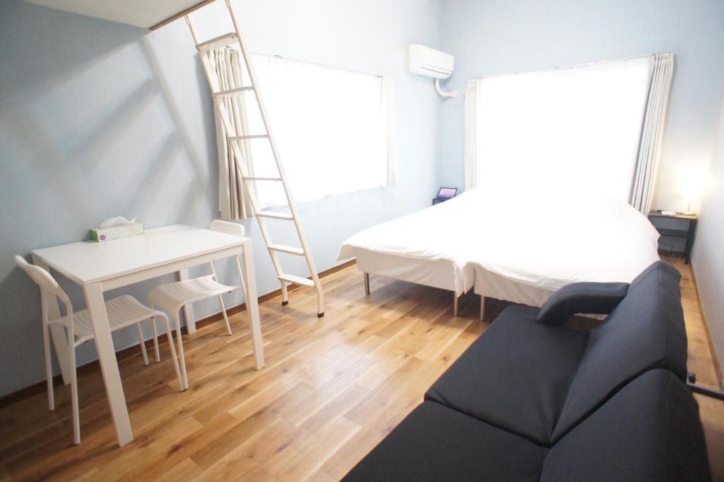 a room with a bed and a desk and a ladder at Plusone Nishikoen in Fukuoka