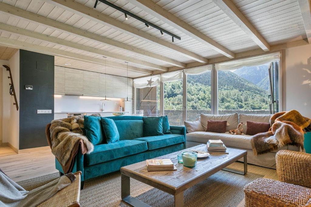 a living room with a blue couch and a table at Luderna - Apartamento con jardín Bela in Vielha