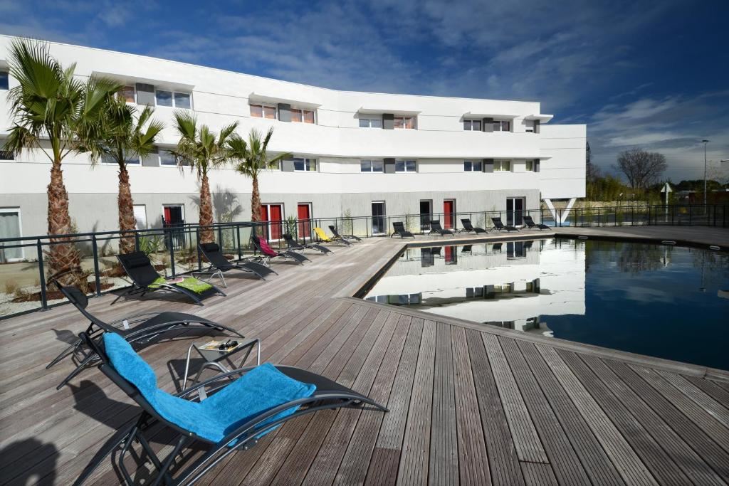 un complexe avec une piscine, des chaises et un bâtiment dans l'établissement Vacancéole - Le Terral - Montpellier Sud, à Saint-Jean-de-Védas