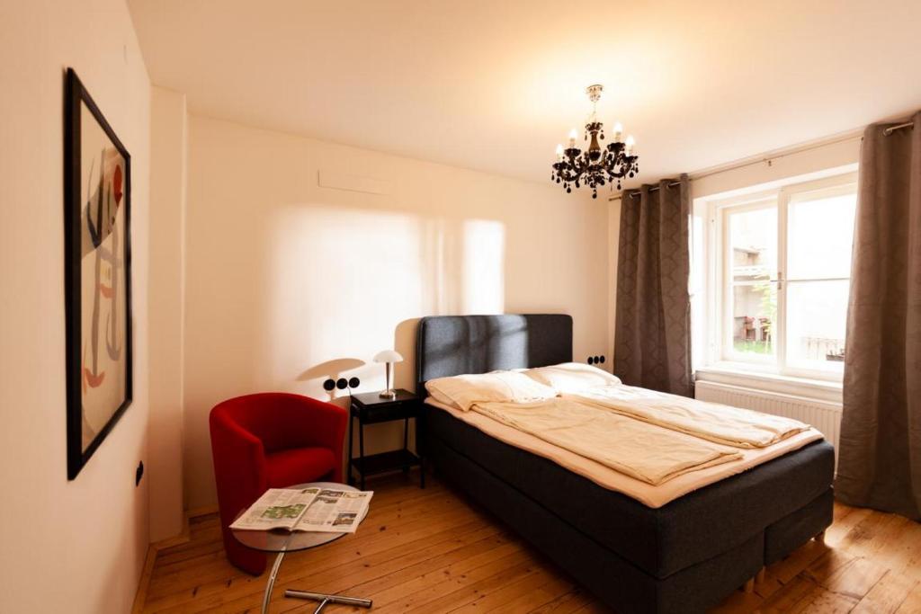 a bedroom with a bed and a red chair at City Appartement in Bad Radkersburg