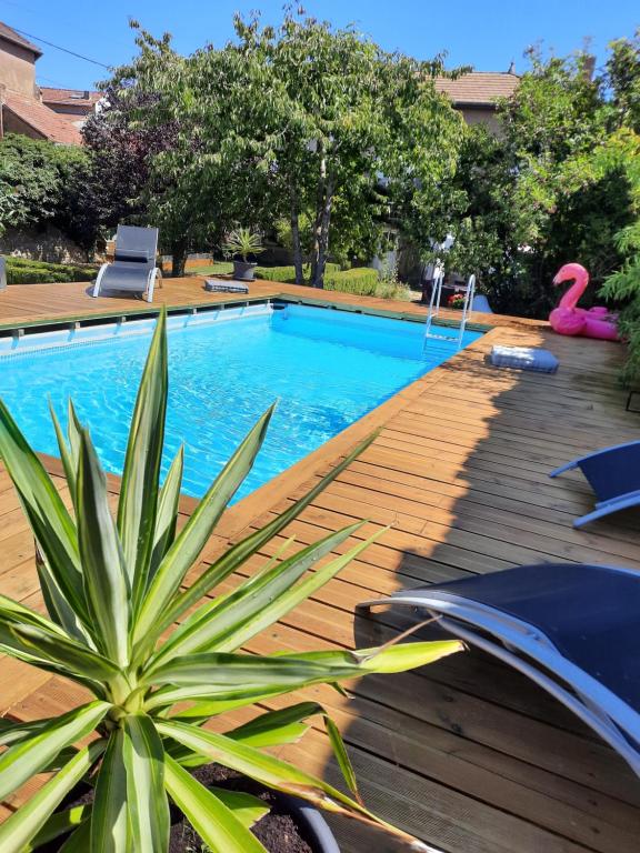 a swimming pool with a wooden deck next to a house at Parenthèse à la campagne in Alaincourt-la-Côte