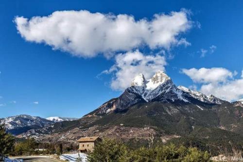 una montaña cubierta de nieve con una casa frente a ella en HOSTAL RURAL CAL XIC Saldes, en Saldes