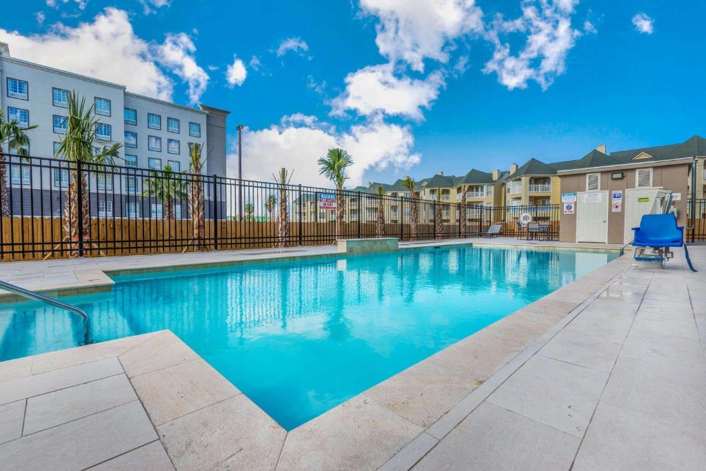 uma piscina num complexo de apartamentos com um céu azul em La Quinta Inn & Suites by Wyndham Galveston West Seawall em Galveston