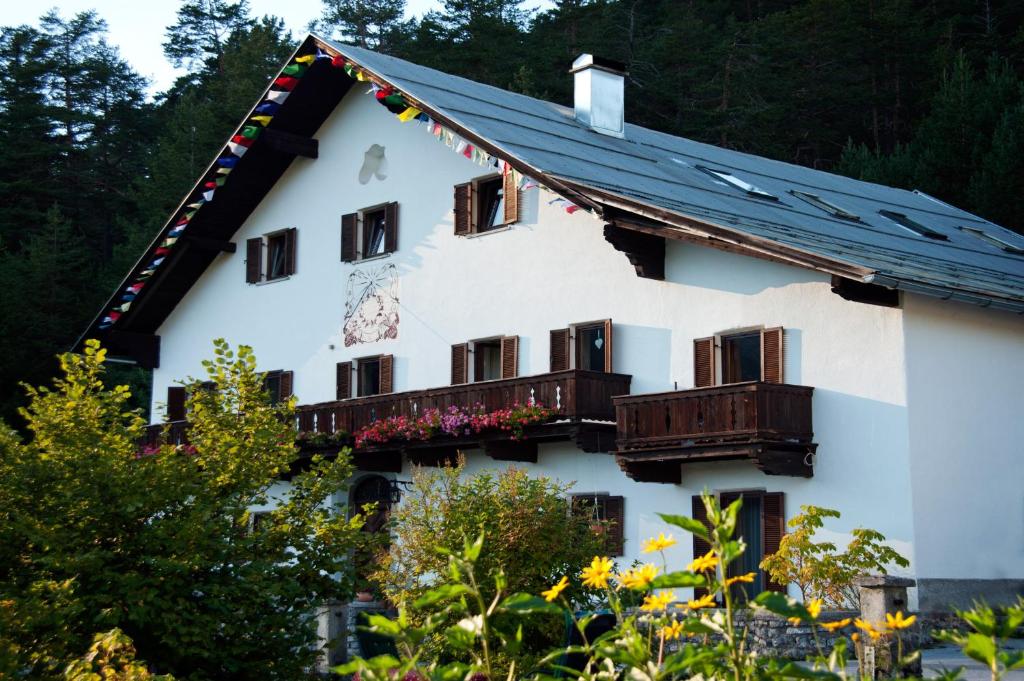 a white house with a balcony and trees at AlpenRetreat in Nassereith