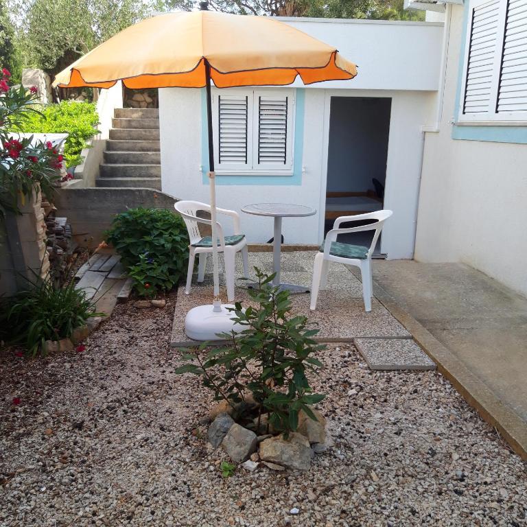 een patio met een tafel, 2 stoelen en een parasol bij Apartment Lib in Lun