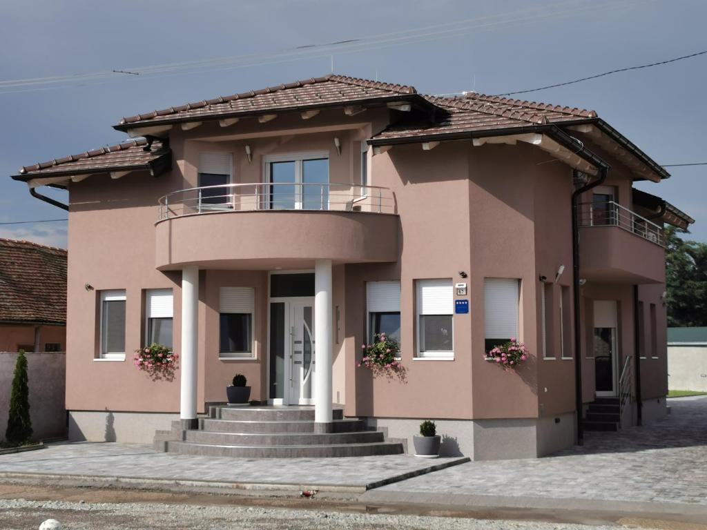 una casa rosa con scale e balcone di Apartman Božur **** a Satnica Ðakovačka