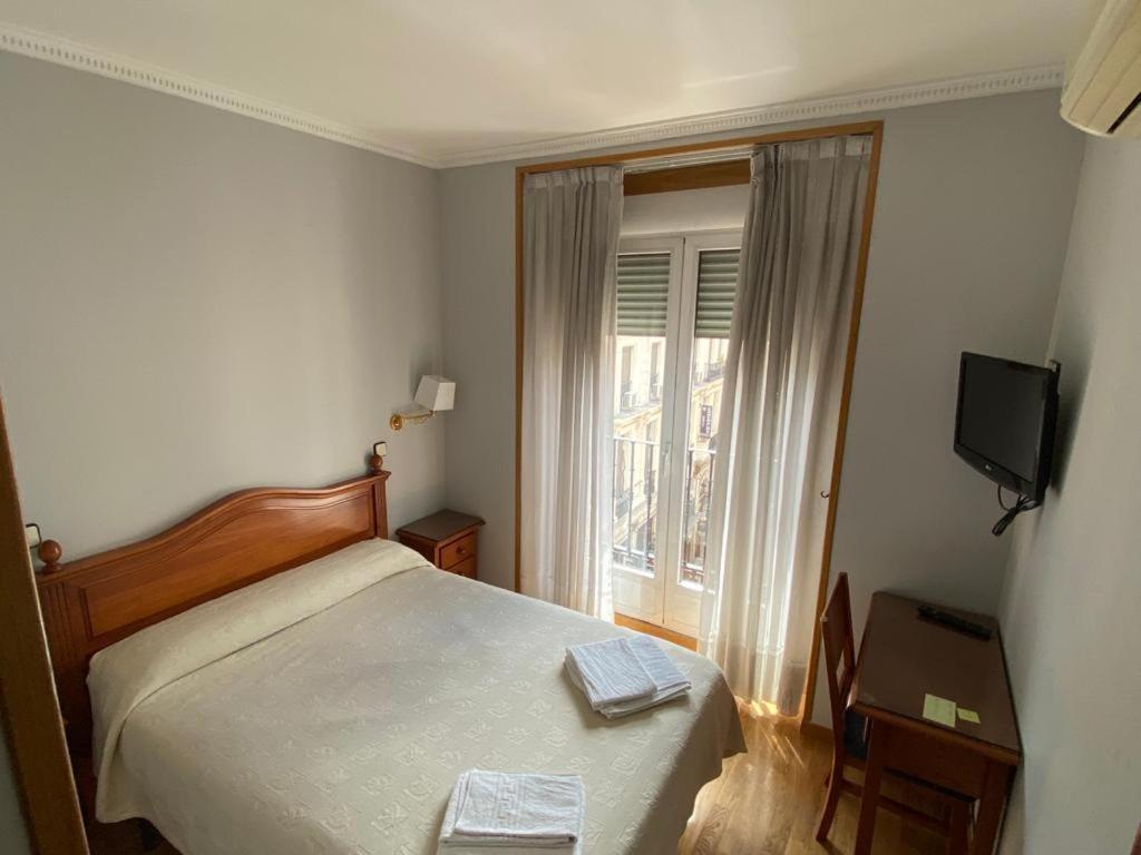 1 dormitorio con 1 cama, TV y ventana en Hostal Guerra, en Madrid