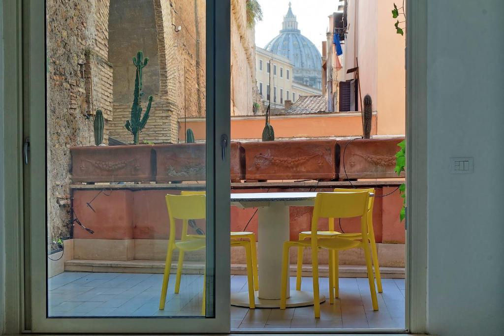 une table et deux chaises jaunes devant une fenêtre dans l'établissement terrazza del pontefice, à Rome