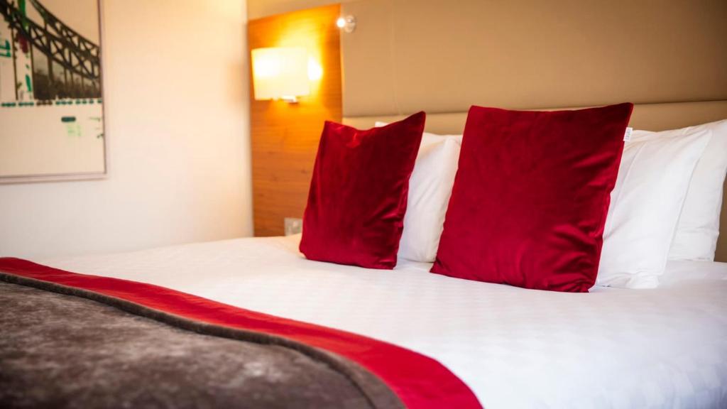 a bed with red pillows in a hotel room at The Tower Hotel, by Thistle in London