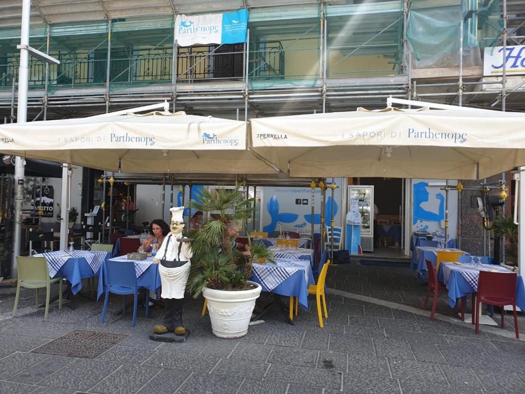 una mujer parada frente a un restaurante con mesas y sombrillas en Casa Sammarco, en Nápoles