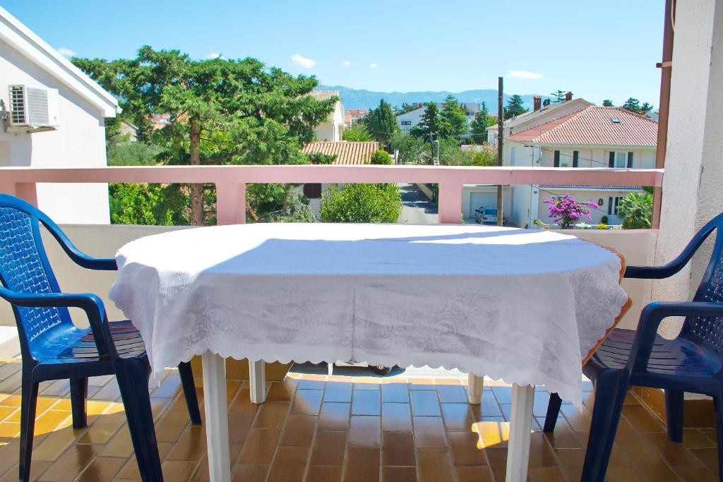 a white table and chairs on a balcony with a view at Apartmani Vidušin in Novalja