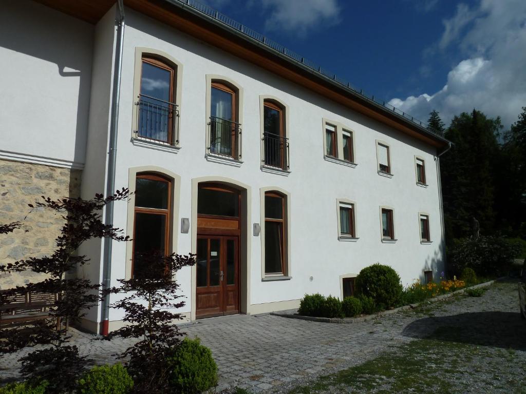 un grande edificio bianco con una porta in legno di Ferienwohnungen am Büchlhof im Oberpfälzer Seenland a Neunburg vorm Wald