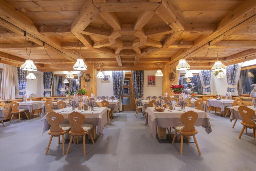 jadalnia ze stołami i krzesłami oraz drewnianymi sufitami w obiekcie Hotel Rascard w mieście Valtournenche