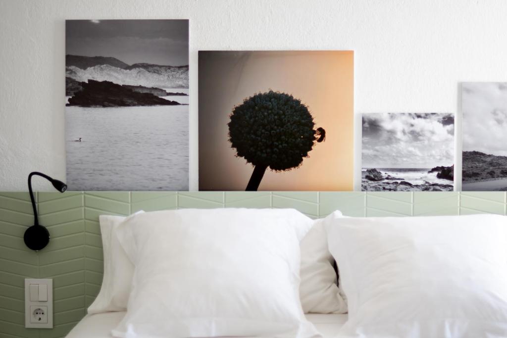 a bedroom with a bed with four pictures on the wall at Mon hotel in Ciutadella