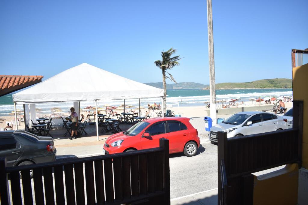 a red car parked next to a beach with a white tent at Apartamento Praia do Peró in Cabo Frio