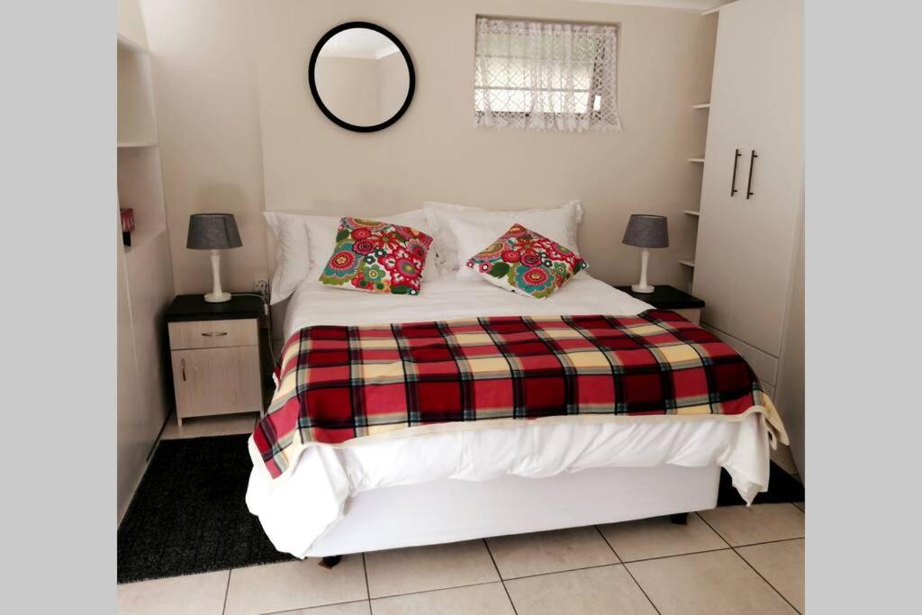 a bedroom with a bed with a plaid blanket at Chelmsford Cottage in Port Elizabeth