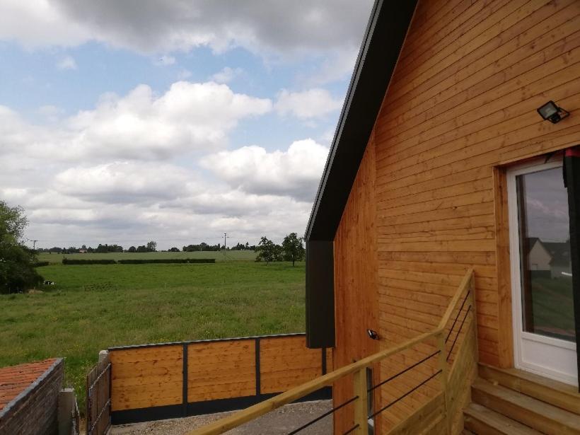 a building with a porch with a field in the background at appartement 1ere étage dans maison individuelle in Saint-Jacques-sur-Darnétal