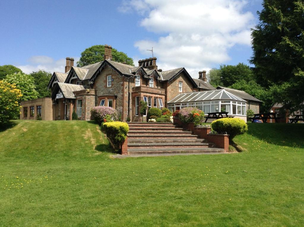 uma casa grande numa colina relvada com escadas em Arden House Hotel em Kirkcudbright