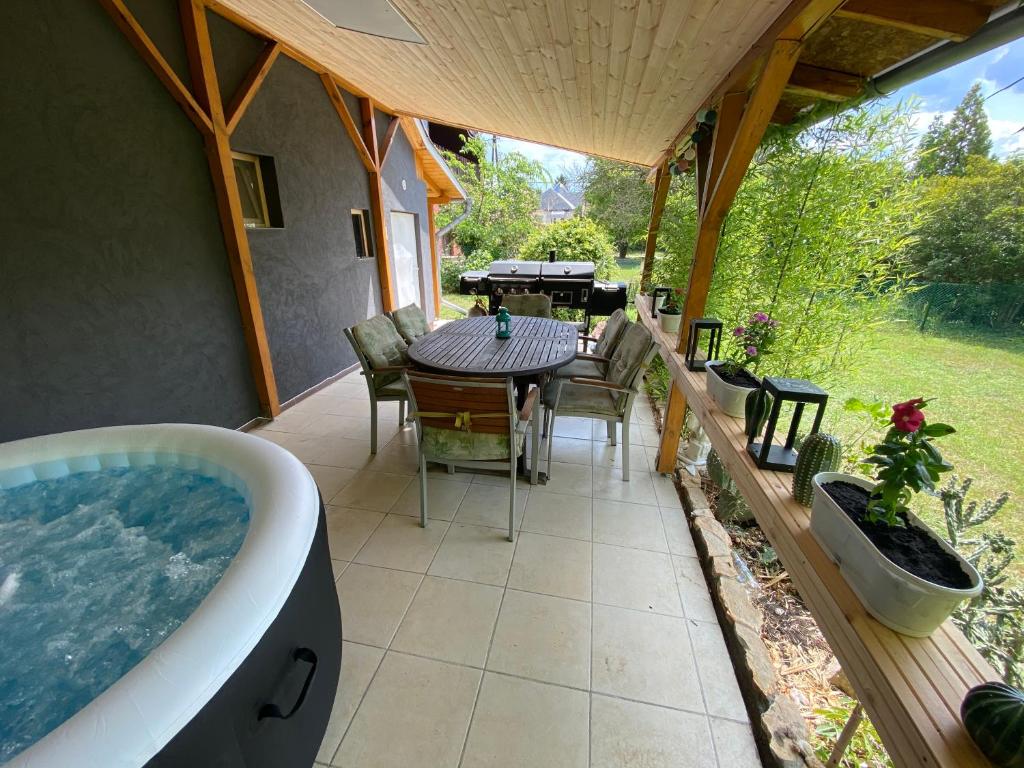 d'une terrasse avec une baignoire, une table et des chaises. dans l'établissement Vintage Jakuzzis Vendégház, à Gárdony