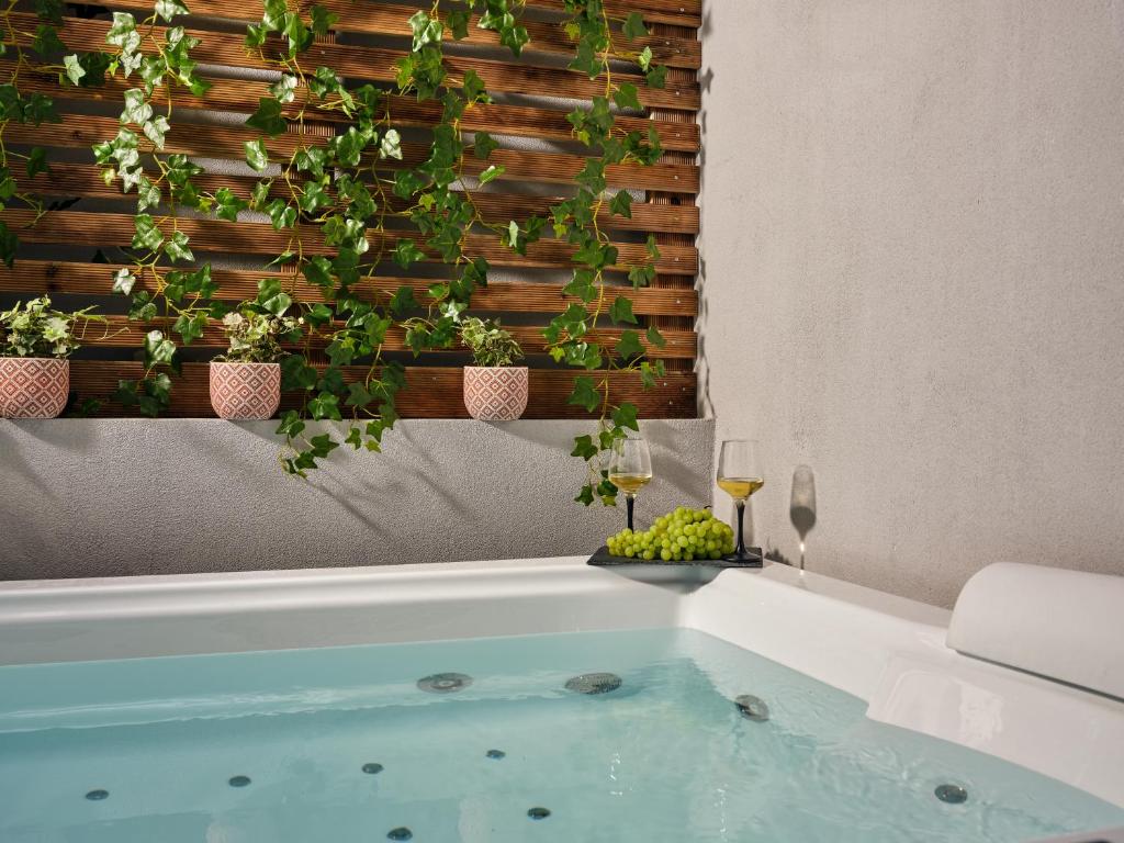 a bathroom with a tub with plants on a wall at Pothos Suites in Zakynthos Town