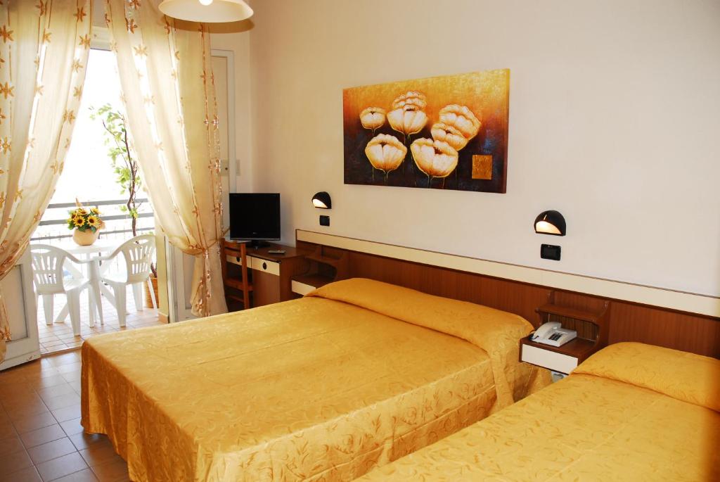 チェゼナーティコにあるHotel Devon Rooms & Breakfastのベッドルーム1室(ベッド2台付)が備わります。壁にドーナツの写真が飾られています。