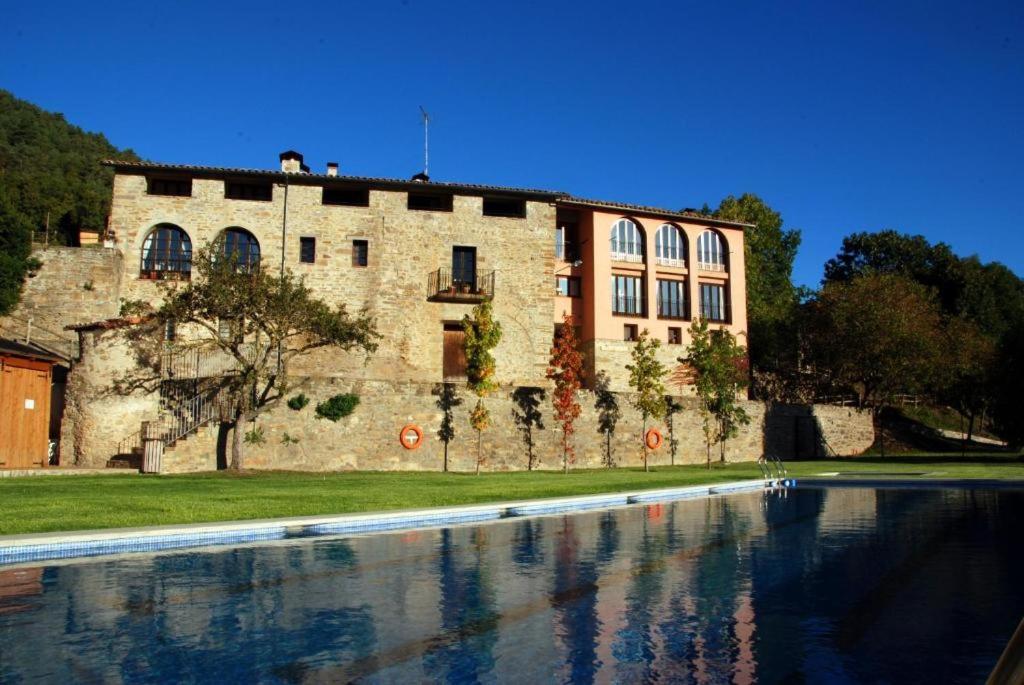 un edificio con una piscina de agua frente a un edificio en CAMPALANS Hotel Rural Bungalows Mobilhomes en Borredá