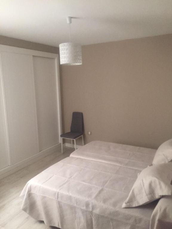 Un dormitorio con una cama blanca y una silla. en Apartamento Centro Merced, en Ronda