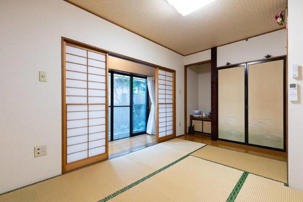 Noriko's Home - Vacation STAY 8643 في كاواساكي: غرفه فاضيه فيها ابواب ونوافذ وسجاده