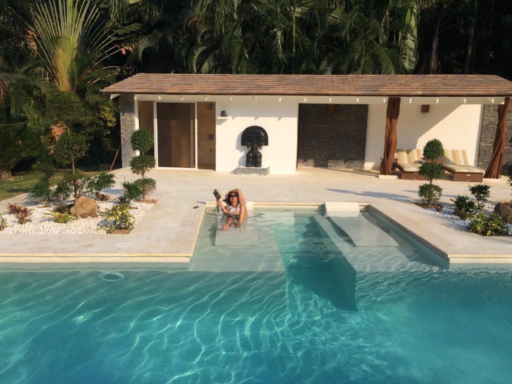 una mujer está sentada en una piscina en Las Terrenas Front Beach And Garden Villa en Las Terrenas
