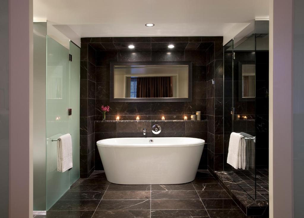 a bath tub in a bathroom with black tiles at Rosewood Hotel Georgia in Vancouver