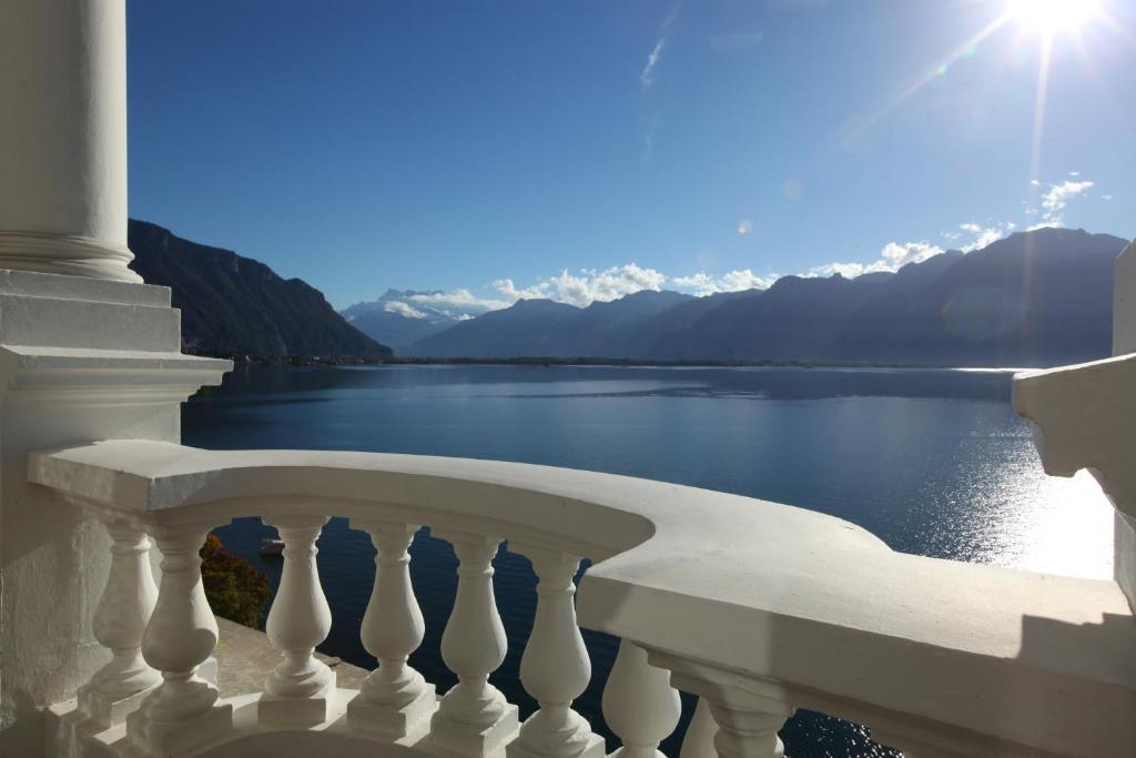 uma varanda com vista para a água e para as montanhas em Hôtel du Grand Lac Excelsior em Montreux