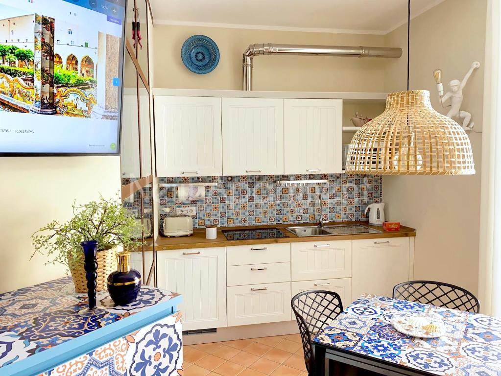ナポリにあるCaprese Experience - Light Blu Apt - Danteのキッチン(白いキャビネット、テーブル、椅子付)