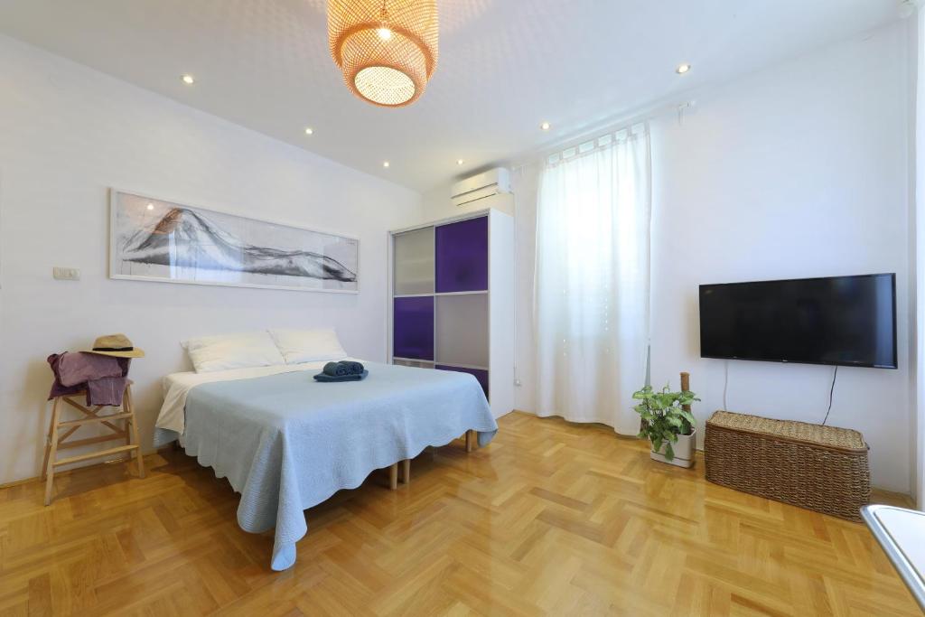 a bedroom with a bed and a flat screen tv at Lovely Rita's Sibenik - apartment city center in Šibenik