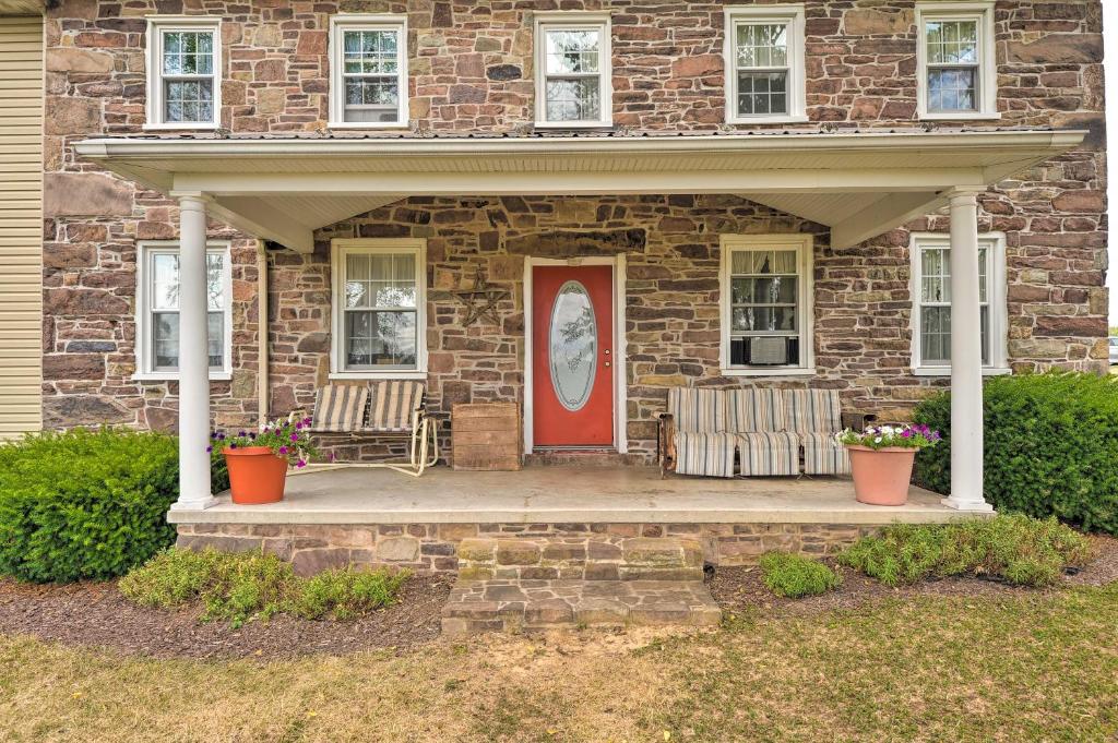 una casa de ladrillo con puerta roja y 2 sillas en Farmhouse on River, 12 Miles to Liberty Mountain, en Taneytown