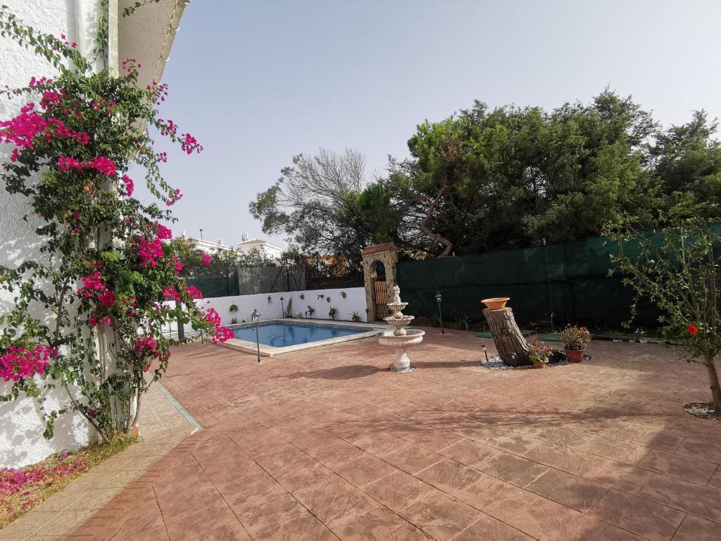 a backyard with a swimming pool and pink flowers at Entre pinos y playa in Matalascañas