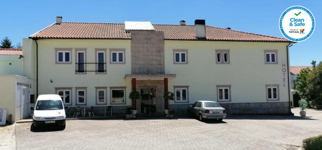 una grande casa bianca con due auto parcheggiate in un parcheggio di A Vileira a Vimioso