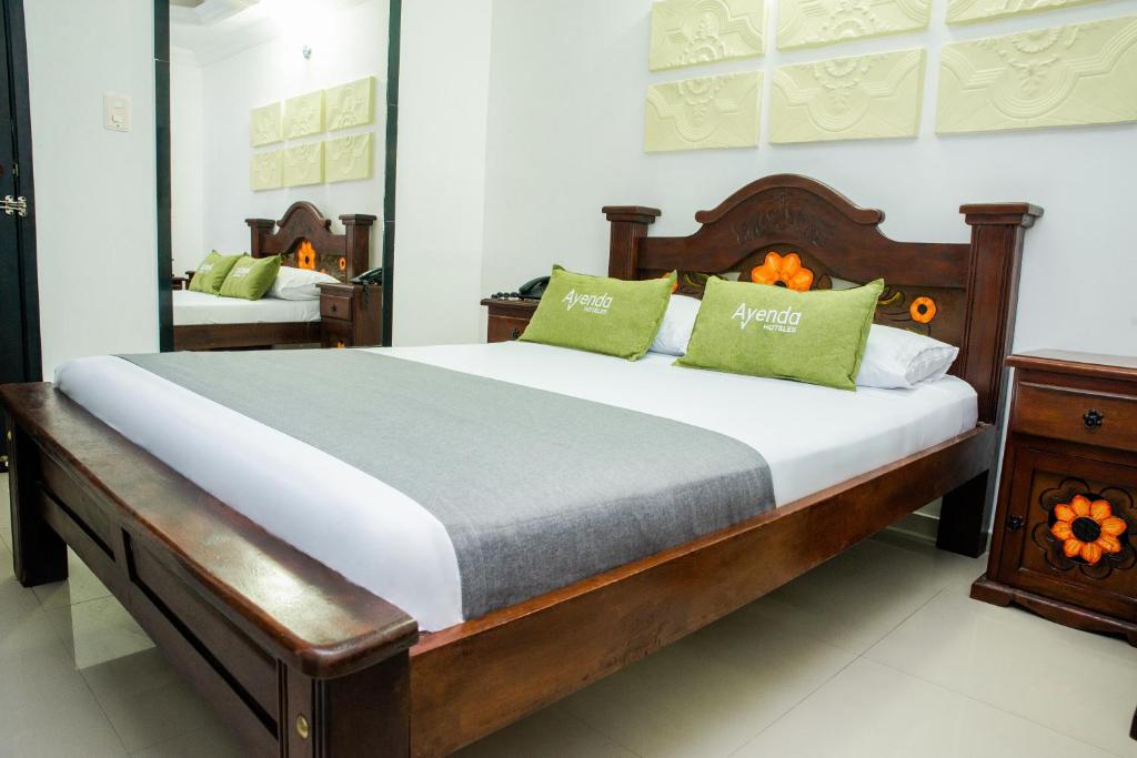1 dormitorio con 1 cama grande con almohadas verdes en Ayenda 1315 Candiac, en Barranquilla