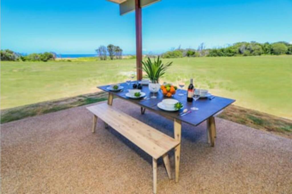 a picnic table with a bench on a patio at Ocean View Absolute Beachfront 2-Bedroom Home in Deepwater