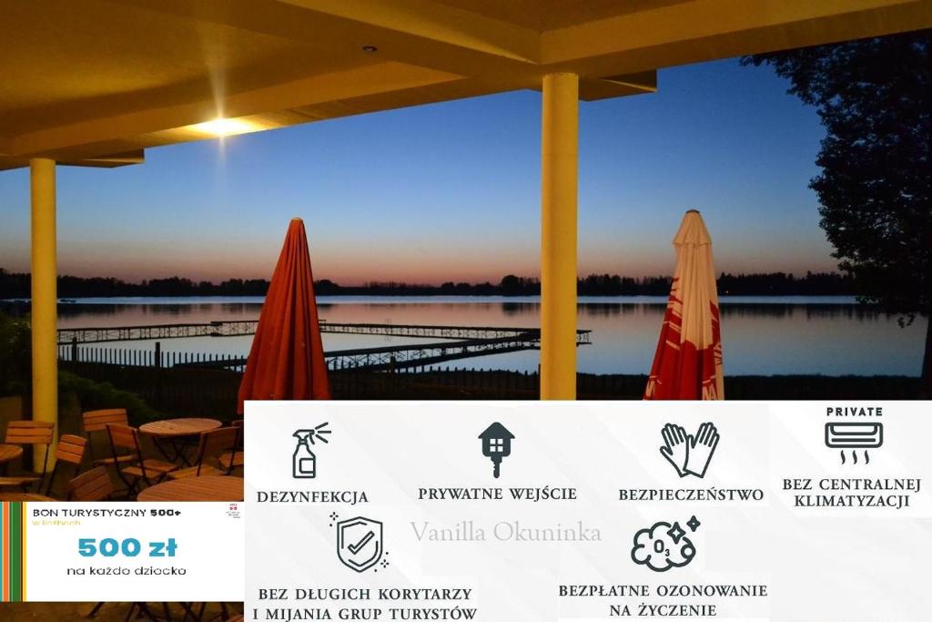 オクニンカにある"Vanilla" Pokoje i Apartamenty Nad Brzegiem Jezioraの傘付きのレストランから湖の景色を望めます。