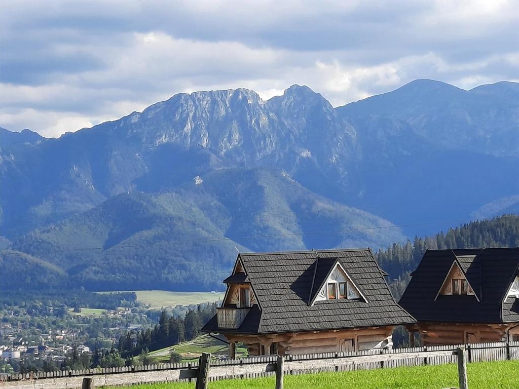 a house on a hill with mountains in the background at Góralskie Domki Zakopane Gubałówka in Zakopane