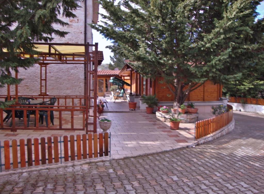 a brick sidewalk with a fence and trees and a building at La Casetta Dei Sogni D'Oro in Castellana Grotte