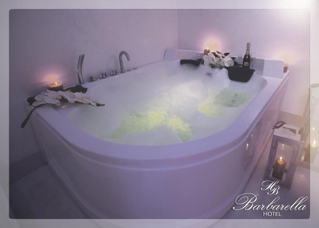 a white bath tub with flowers and candles in it at Barbarella HOTEL SPA in Naples