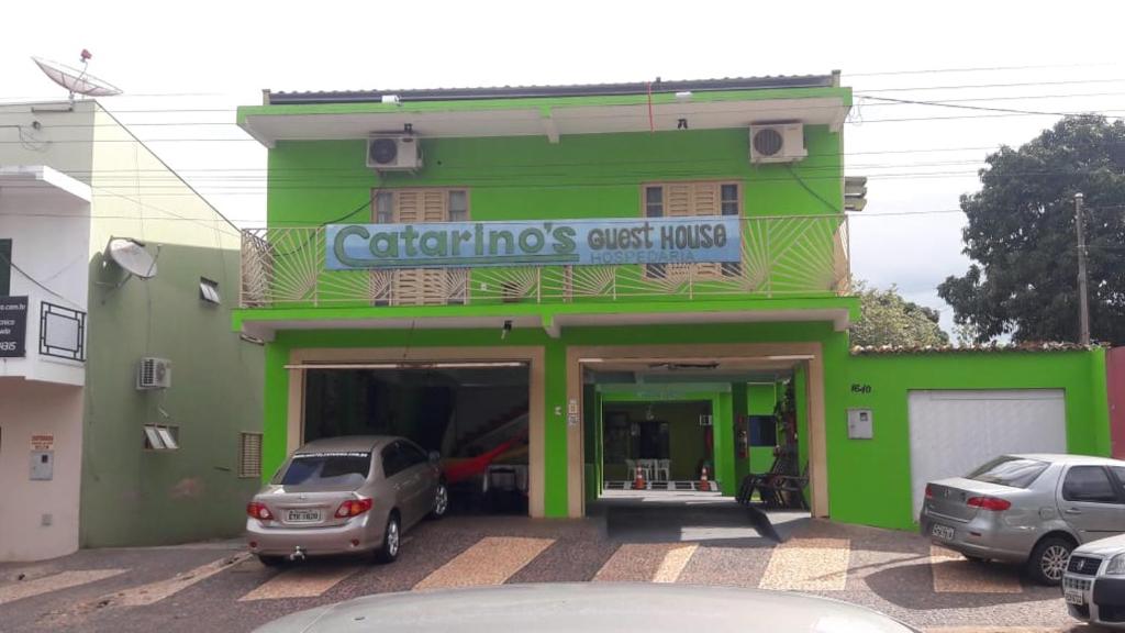 a green building with cars parked in front of it at Pousada Catarinos hostel in Bonito