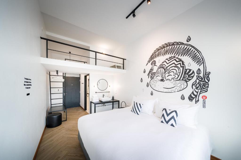 Blu Monkey Hub & Hotel Ranong في رانونغ: غرفة نوم مع سرير أبيض مع لوحة جدارية على الحائط