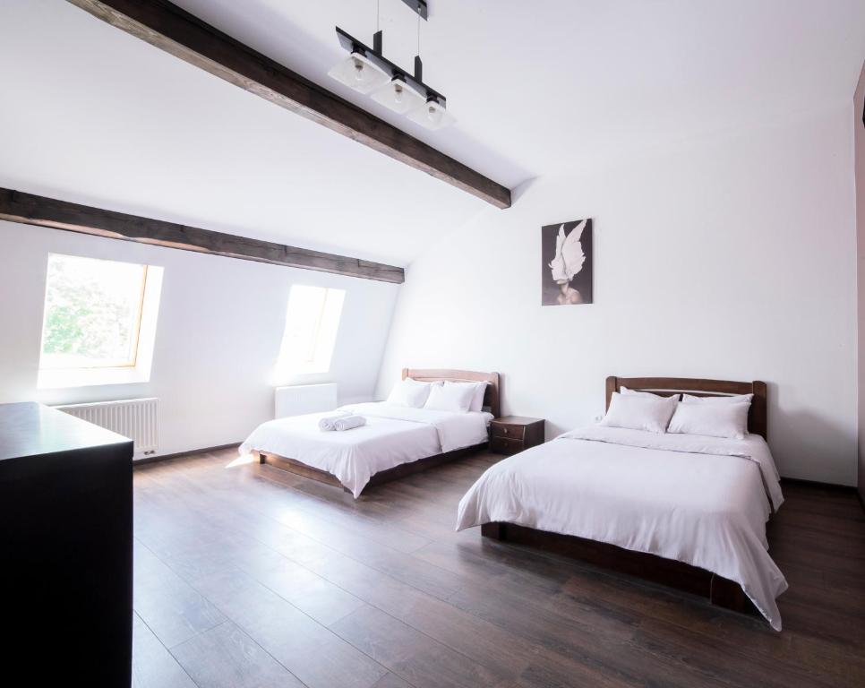 リヴィウにあるApartment on Lychakivskaの白い壁とウッドフロアの客室で、ベッド2台が備わります。