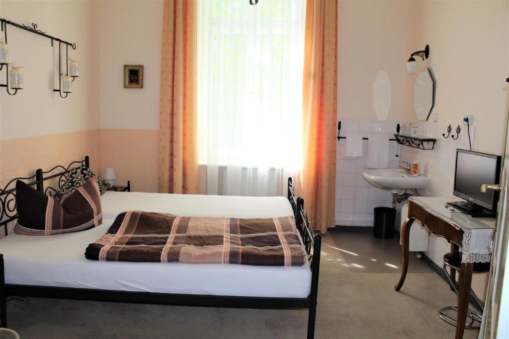 a bedroom with a bed and a desk and a sink at Pension Brinn in Berlin