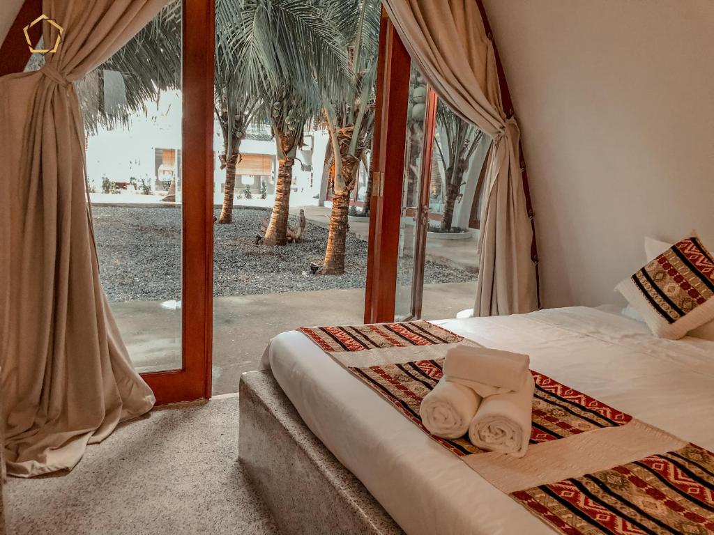 a bedroom with a bed and a window with palm trees at SaoConDor Hotel in Con Dao