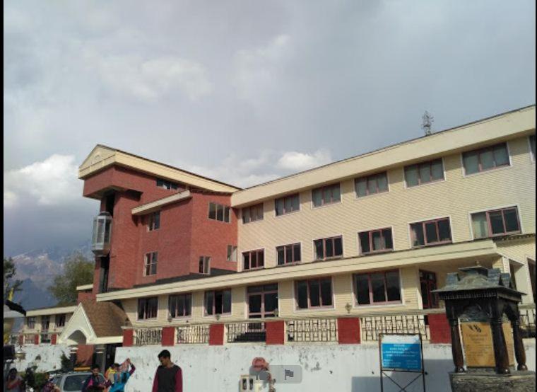 a large building with people walking in front of it at GMVN Auli in Joshīmath